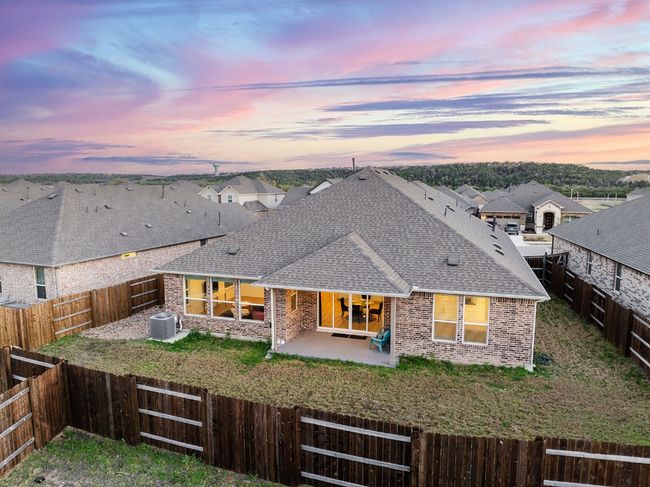 Back of property at dusk with brick siding, central AC, roof with shingles, a fenced backyard, and a patio area | Image 31