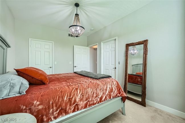 Bedroom featuring light colored carpet, baseboards, a notable chandelier, and visible vents | Image 19