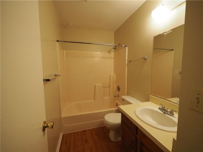 Bathroom featuring toilet, wood finished floors, vanity, and washtub / shower combination | Image 12
