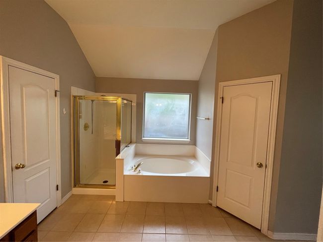 Bathroom with lofted ceiling, a garden tub, a stall shower, tile patterned floors, and vanity | Image 27