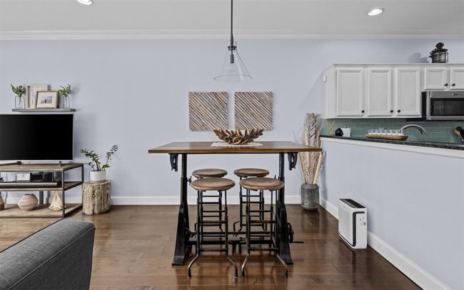 Kitchen with dark countertops, white cabinetry, ornamental molding, stainless steel microwave, and dark wood-style flooring | Image 5