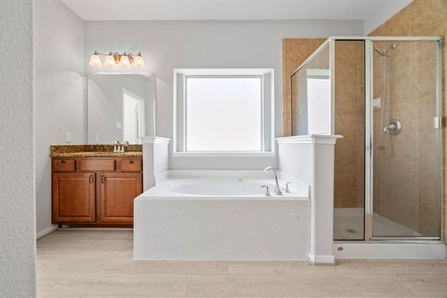 The luxurious master bathroom offers a spa-like retreat with elegant finishes throughout. Enjoy the comfort of dual vanities, a spacious walk-in shower, and a deep soaking tub perfect for unwinding. Large walk-in closet complete this serene and stylish space designed for relaxation and convenience. | Image 18