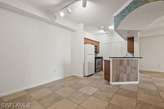 Kitchen featuring range, rail lighting, freestanding refrigerator, light tile patterned flooring, and brown cabinets | Image 11