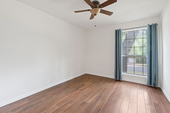 One of three secondary bedrooms, all with closet storage, ceiling fans, and tile plank flooring. | Image 26