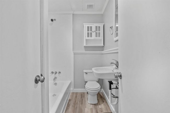 Bathroom with wood finished floors, ornamental molding, and shower / bath combination | Image 13
