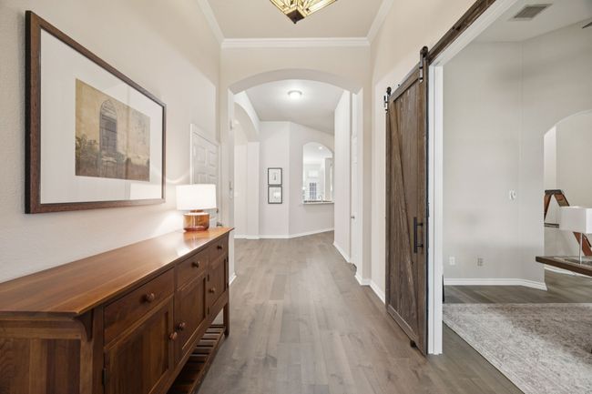 Arched transitions and decorative wall niches add architectural interest, while the barn doors to the left create a statement entry to the home office. | Image 4