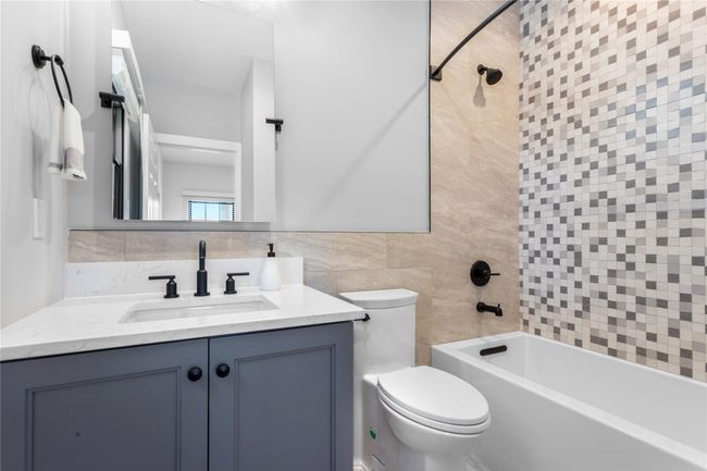 Bathroom with toilet, vanity, tile walls, and shower / bathtub combination | Image 16