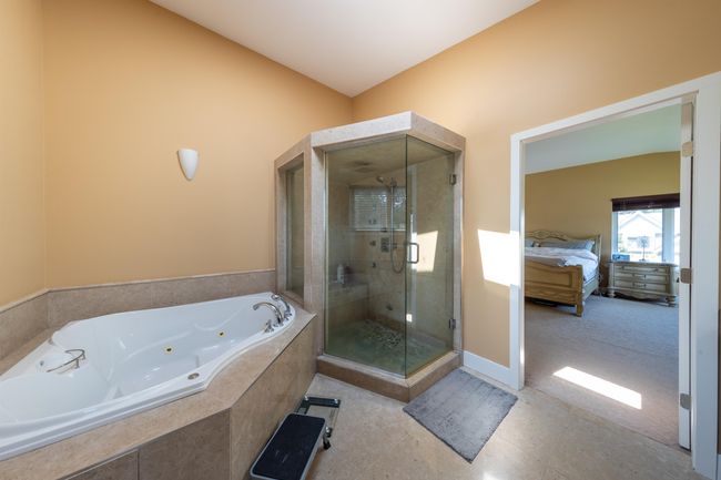 Ensuite bathroom featuring a whirlpool tub, a stall shower, and baseboards | Image 28