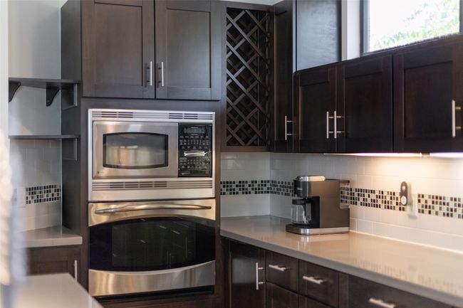 Kitchen featuring backsplash, appliances with stainless steel finishes, and dark brown cabinetry | Image 11