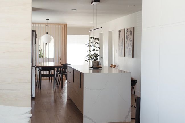 Kitchen featuring modern cabinets, dark wood-type flooring, a center island, decorative light fixtures, and light stone counters | Image 9