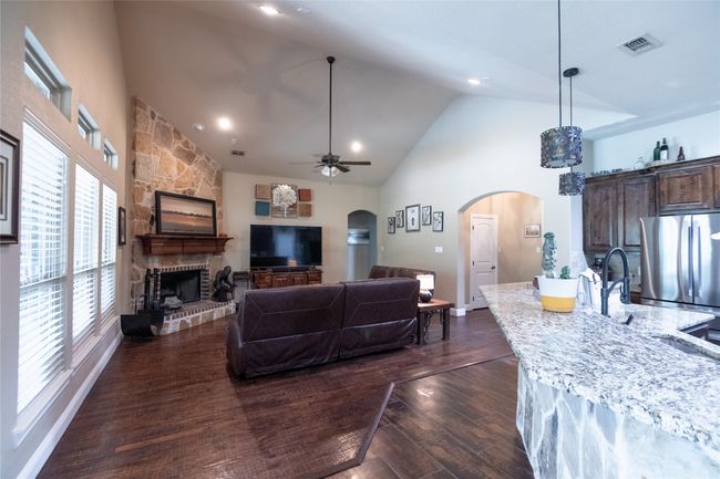 Living room featuring arched walkways, high vaulted ceiling, a fireplace, dark wood-style flooring, and ceiling fan | Image 12
