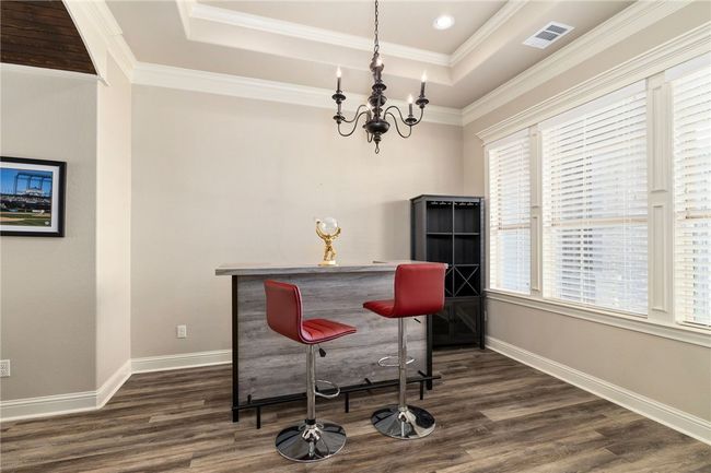 This beautiful dining area features elegant vinyl flooring, a large window that floods the space with natural light, and a stunning chandelier that adds a touch of sophistication. | Image 4