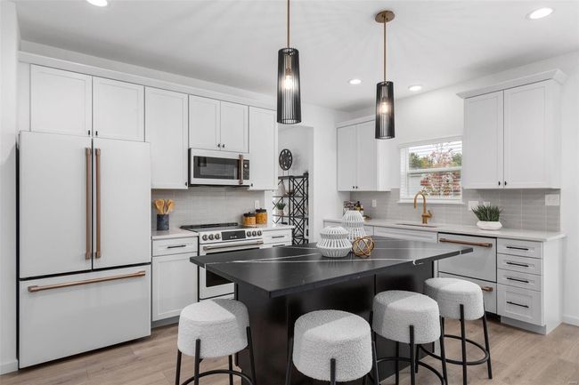 Kitchen featuring white cabinets, white appliances, a center island, and sink | Image 26