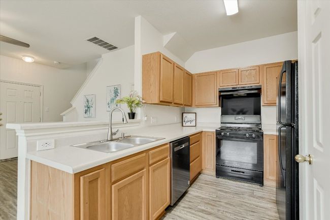 Kitchen featuring light wood-style floors, black appliances, light brown cabinetry, and light countertops | Image 13