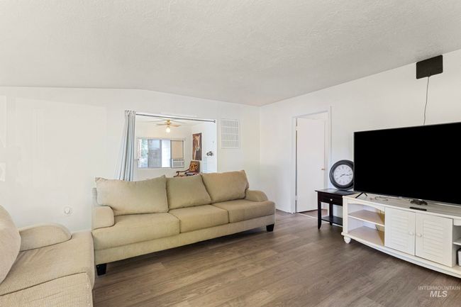 Living area with dark wood finished floors, a textured ceiling, and cooling unit | Image 12