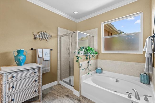 Bathroom featuring a stall shower, a garden tub, ornamental molding, and baseboards | Image 28