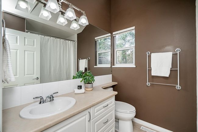 Bathroom featuring visible vents, baseboards, a shower with curtain, toilet, and vanity | Image 16