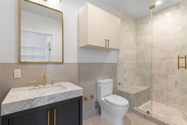 Full bathroom with tile walls, toilet, a shower stall, vanity, and tile patterned floors | Image 29