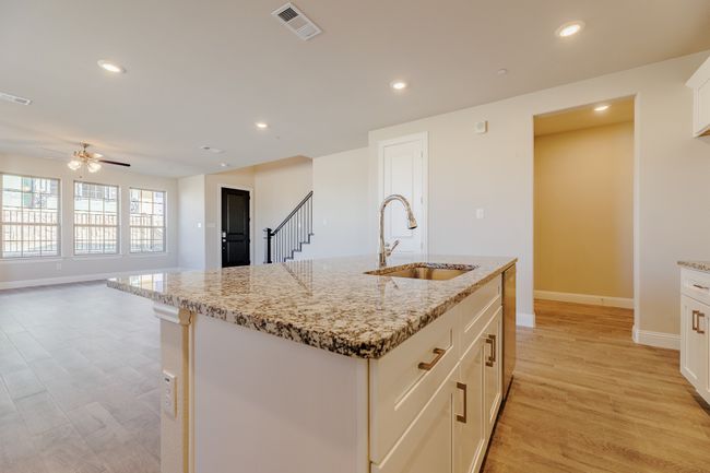 Kitchen featuring light wood-style flooring, recessed lighting, light stone counters, a ceiling fan, and a kitchen island with sink | Image 12