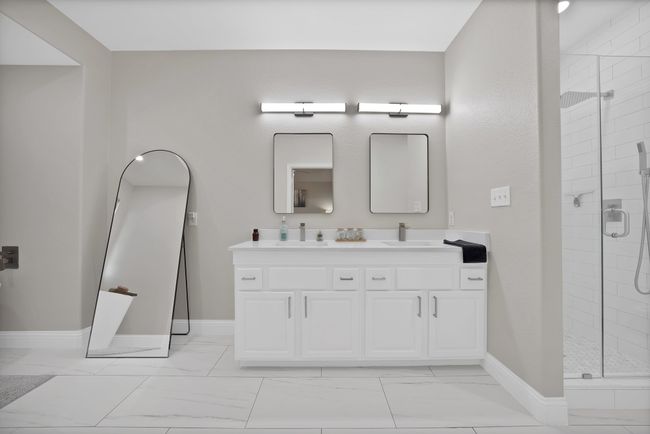 Bathroom with double vanity, a stall shower, marble look tile flooring, and baseboards | Image 33