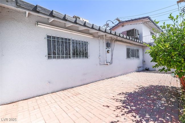 View of side of home with stucco siding, a patio area, and a tile roof | Image 54