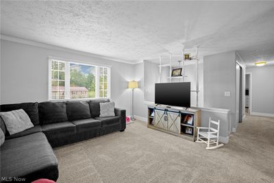 Carpeted living room featuring ornamental molding and a textured ceiling | Image 2