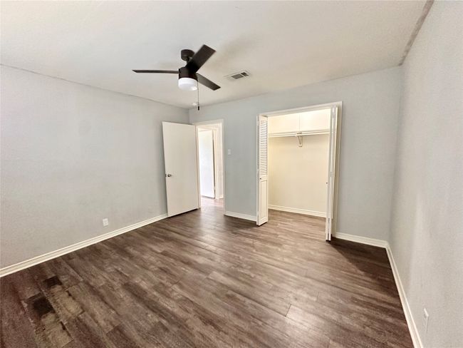 Unfurnished bedroom featuring dark wood-style flooring, a closet, and ceiling fan | Image 24