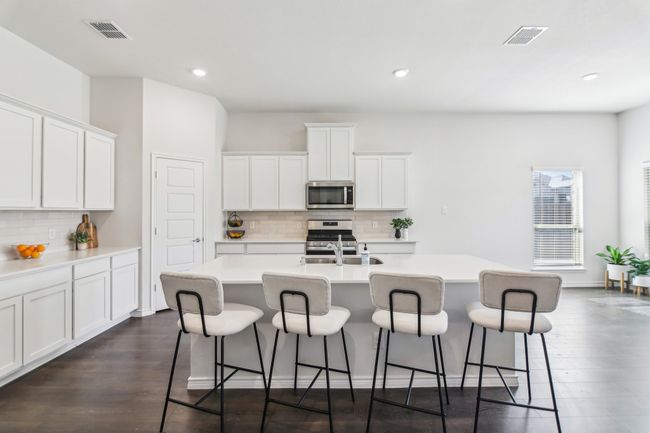 Kitchen featuring visible vents, appliances with stainless steel finishes, a kitchen island with sink, and a kitchen bar | Image 9