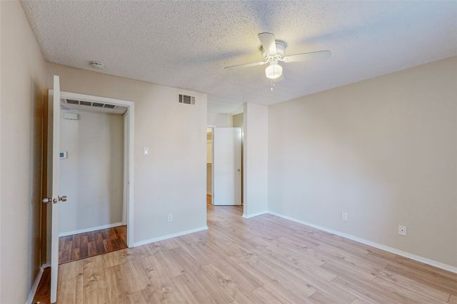 A vacant bedroom with polished hardwood floors and a ceiling fan offering a bright and open feel. | Image 19