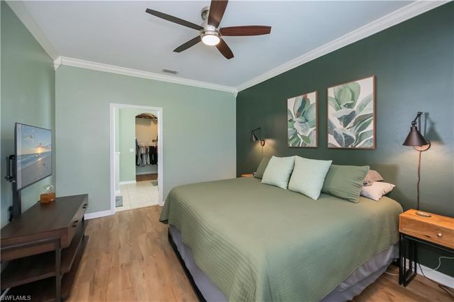 Bedroom with crown molding, visible vents, wood finished floors, baseboards, and a ceiling fan | Image 15