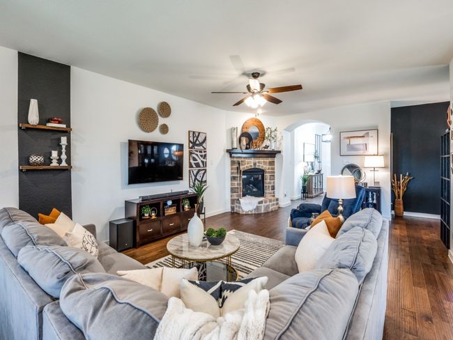 Living room featuring wood finished floors, a glass covered fireplace, ceiling fan, arched walkways, and baseboards | Image 9