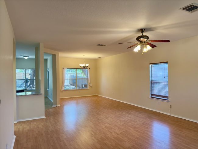 Spare room featuring a chandelier, wood finished floors, healthy amount of natural light, and ceiling fan | Image 16