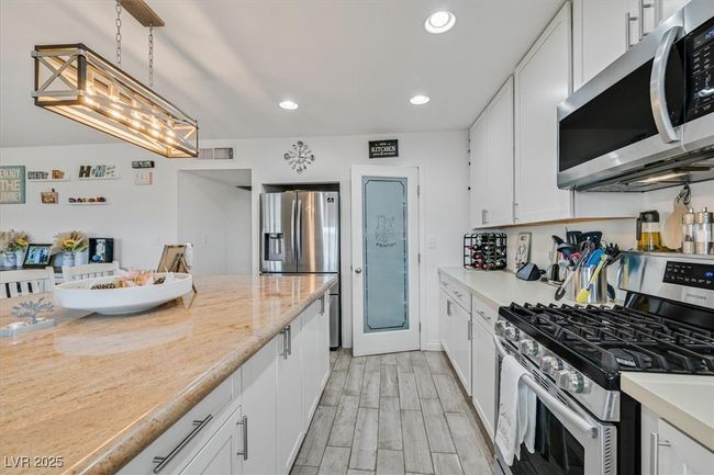 Kitchen with visible vents, wood finish floors, recessed lighting, appliances with stainless steel finishes, and white cabinetry | Image 9