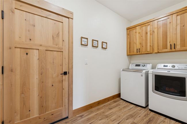 Clothes washing area with washer and dryer, light wood-type flooring, baseboards, and cabinet space | Image 10
