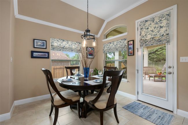 Dining area featuring ornamental molding, vaulted ceiling, light tile patterned floors, and a chandelier | Image 16