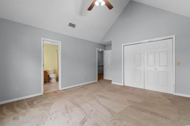 Unfurnished bedroom with high vaulted ceiling, carpet flooring, a closet, ensuite bath, and ceiling fan | Image 24