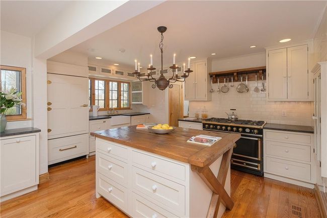 Renovated eat-in kitchen, white inset cabinetry, granite counters, large center island with thick wood plank top, La Cornue 6 burner gas range with double oven, Subzero refrigerator with integral door panel and custom door hardware, oak floors, recessed lighting, pantry, side door entry | Image 14