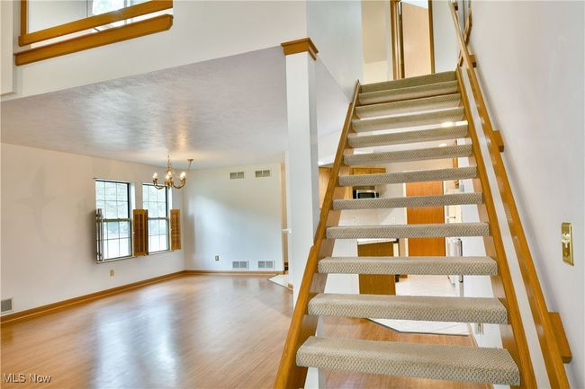 Staircase with a chandelier and wood finished floors | Image 17