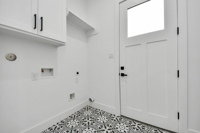 The laundry room features tile floors, washer and dryer connections, andplenty of storage space. | Image 28
