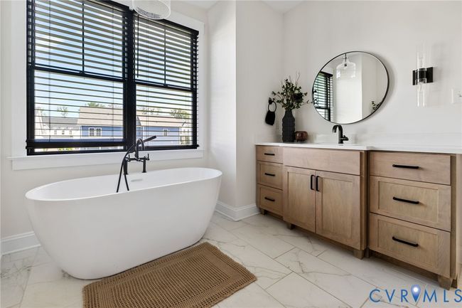 Full bathroom featuring marble look tile flooring, vanity, and a freestanding tub | Image 37