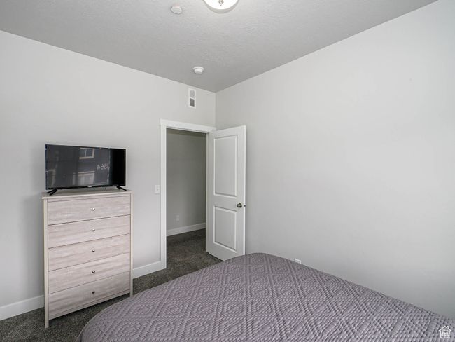 Unfurnished bedroom with baseboards, dark colored carpet, and a textured ceiling | Image 25