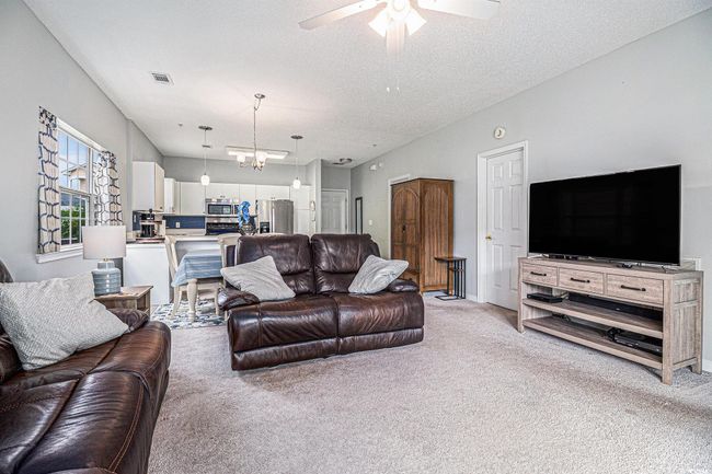 Living room with light carpet, a ceiling fan, and textured ceiling | Image 6