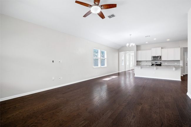 Unfurnished living room featuring a ceiling fan, vaulted ceiling, a chandelier, dark wood-style flooring, and recessed lighting | Image 20