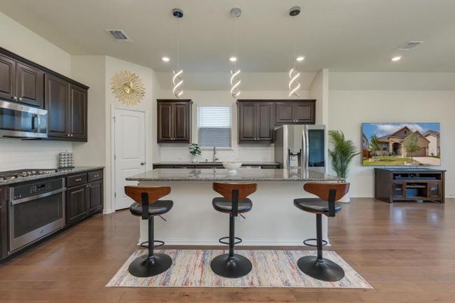 Kitchen featuring appliances with stainless steel finishes, light stone countertops, a sink, backsplash, and recessed lighting | Image 7