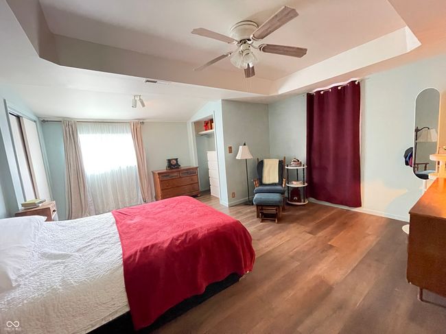 bedroom with wood finished floors, a ceiling fan, and a raised ceiling | Image 7