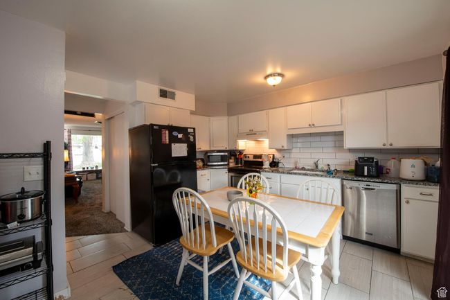 Kitchen with a sink, under cabinet range hood, visible vents, white cabinetry, and appliances with stainless steel finishes | Image 8