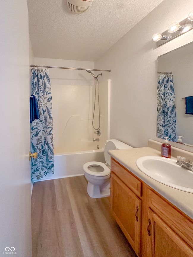 full bath featuring vanity, a textured ceiling, toilet, visible vents, and wood finished floors | Image 23