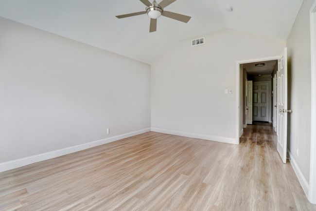 Spare room with a ceiling fan, light wood-style flooring, lofted ceiling, and a smoke detector | Image 15