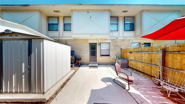 Rear view of house featuring fence, central AC unit, brick siding, an outdoor structure, and a patio area | Image 8