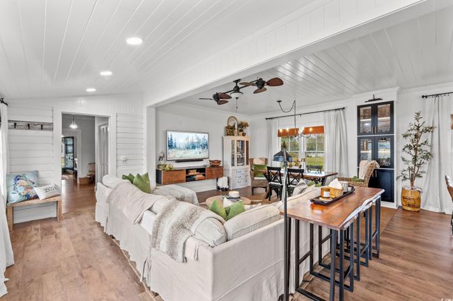 Living area featuring recessed lighting, wood finished floors, crown molding, a ceiling fan, and a chandelier | Image 4